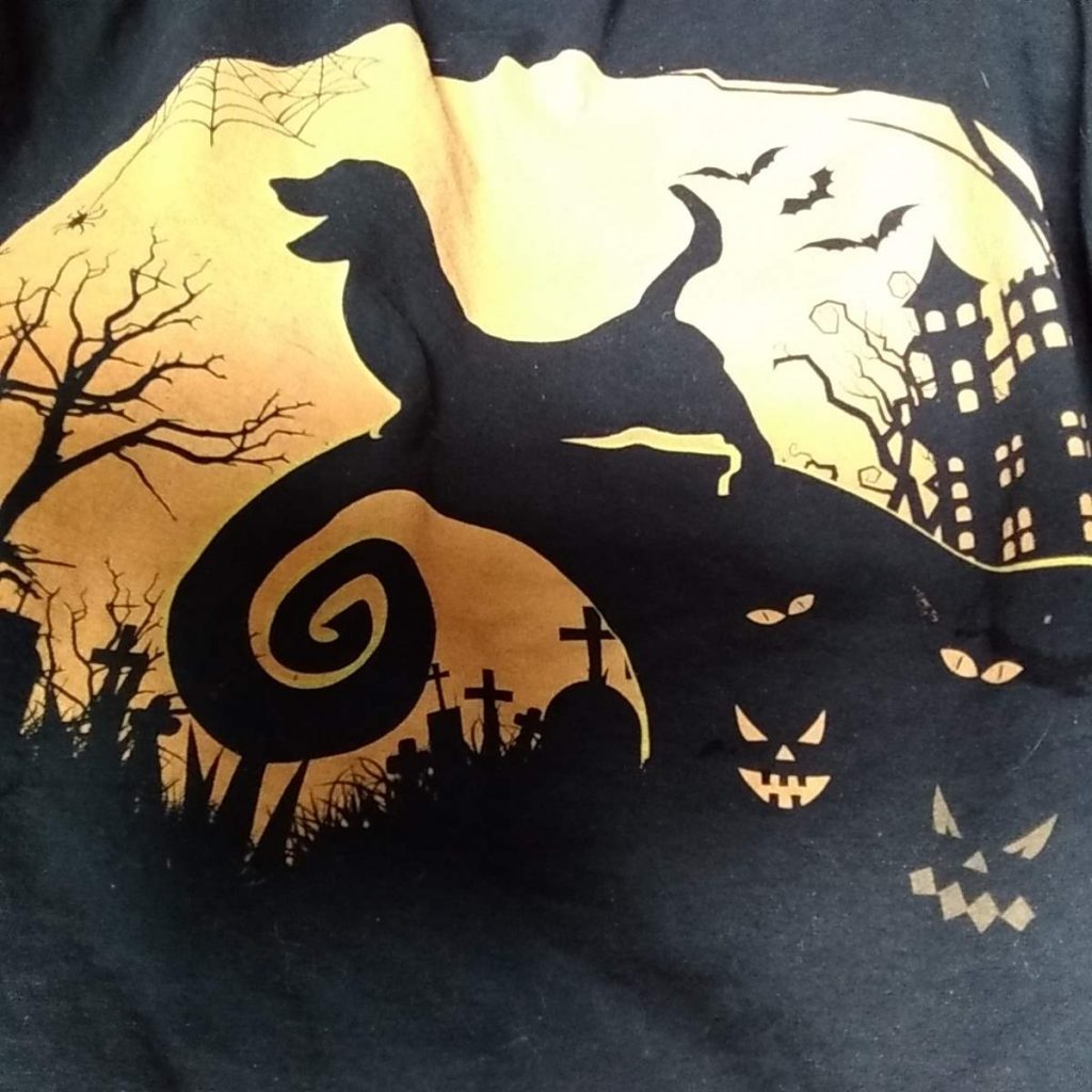 t-shirt with black silhouette of a basset hound baying on a hill, scary creators in the side of the hill, bats flying in the distance  
